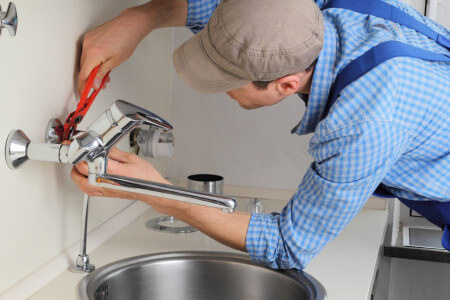 craftsman repairing tap in kitchen