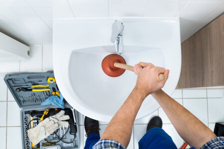 plumber using plunger in sink