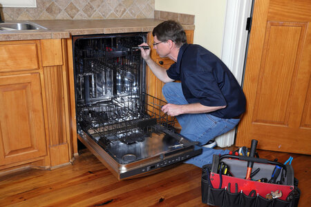 Appliance repairman works on dishwasher