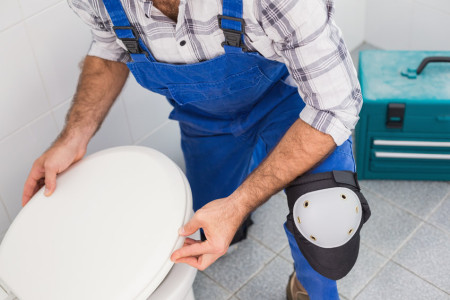 Cheap Plumber installing lid on toilet
