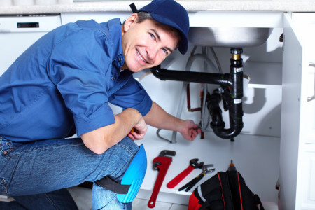Professional plumbing technician under kitchen