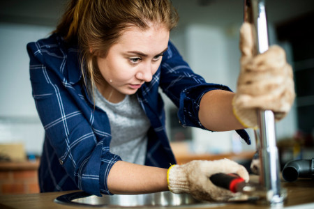 Woman fixing sink in kitchen DIY